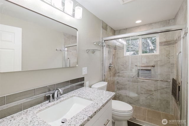 bathroom with toilet, a shower stall, and vanity