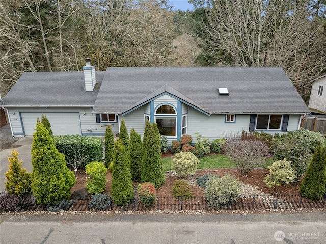 view of front of house featuring a shingled roof, an attached garage, a chimney, and fence