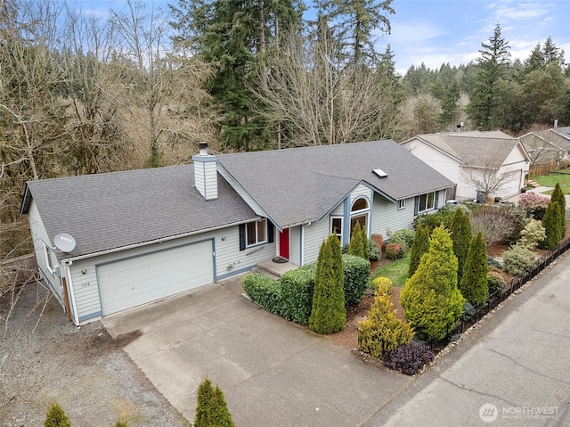 view of front of property featuring roof with shingles, a garage, driveway, and a chimney