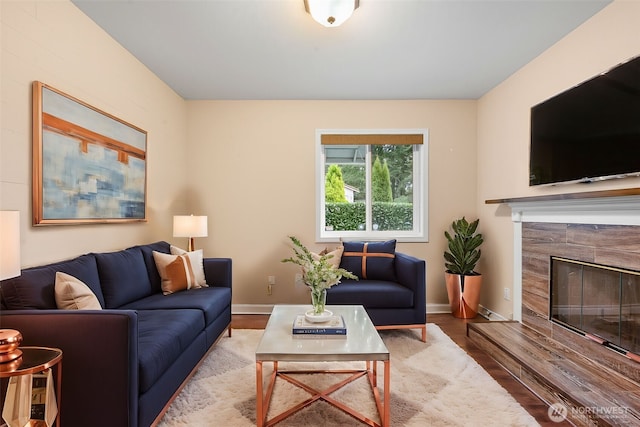 living room with a premium fireplace, baseboards, and wood finished floors