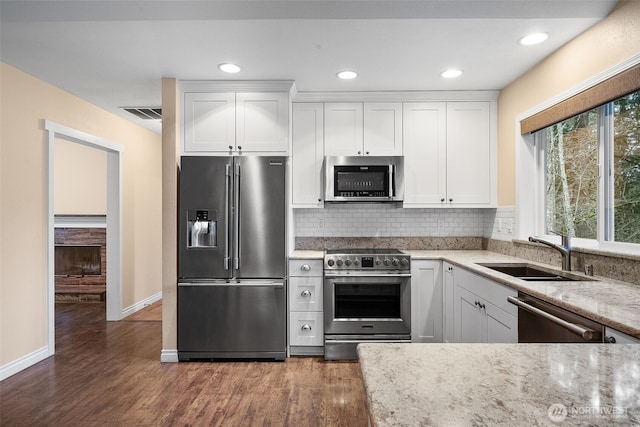 kitchen featuring white cabinetry, decorative backsplash, appliances with stainless steel finishes, and a sink