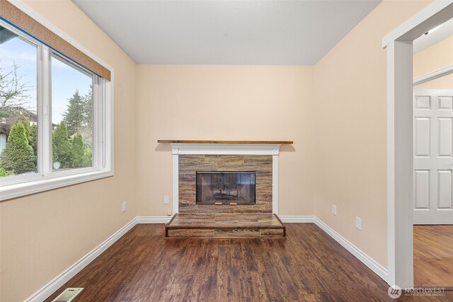 unfurnished living room with visible vents, baseboards, wood finished floors, and a tiled fireplace