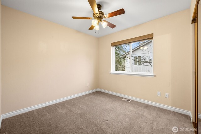 carpeted empty room with visible vents, a ceiling fan, and baseboards