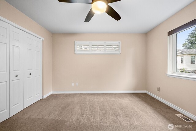 unfurnished bedroom with a closet, multiple windows, visible vents, and carpet floors