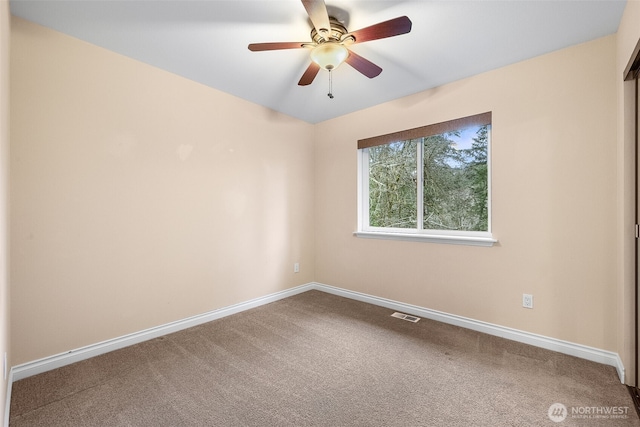 carpeted spare room featuring visible vents, ceiling fan, and baseboards