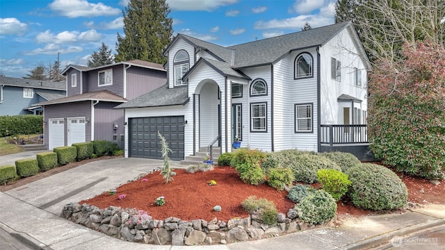 traditional-style home with a garage, driveway, and a shingled roof