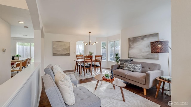 living area featuring a wealth of natural light, baseboards, a chandelier, and dark wood finished floors