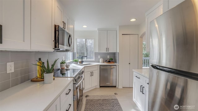 kitchen featuring a sink, recessed lighting, stainless steel appliances, white cabinets, and decorative backsplash