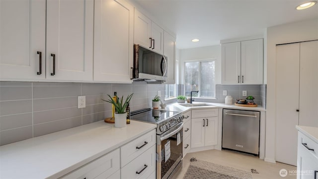 kitchen featuring backsplash, appliances with stainless steel finishes, white cabinetry, and a sink