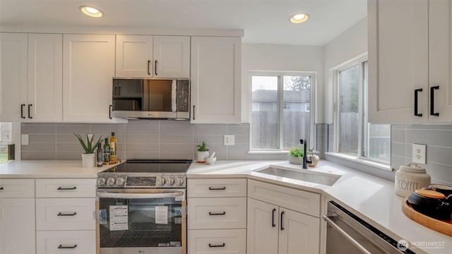 kitchen featuring a sink, decorative backsplash, light countertops, white cabinets, and stainless steel appliances