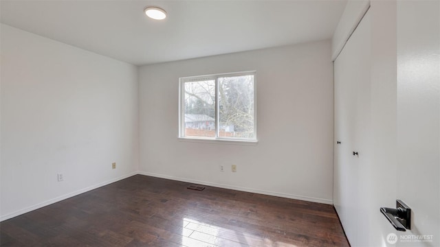 empty room with visible vents, baseboards, and wood finished floors