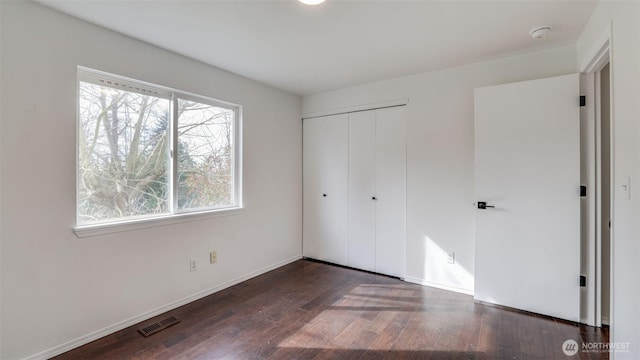 unfurnished bedroom featuring a closet, visible vents, baseboards, and wood finished floors