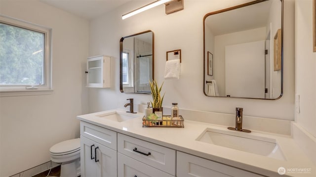 bathroom with double vanity, toilet, and a sink