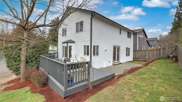 rear view of property with a lawn, a deck, and fence