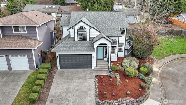 view of front of property with fence, driveway, and roof with shingles