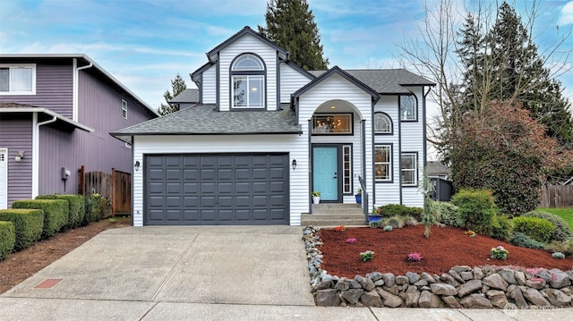 traditional-style home with roof with shingles, driveway, and fence