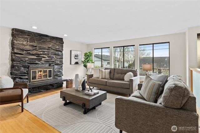 living area featuring a stone fireplace, recessed lighting, and wood finished floors