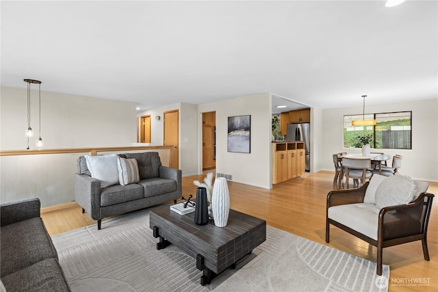 living area with visible vents, baseboards, and light wood-style flooring