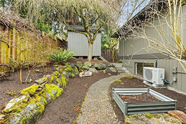 view of yard featuring an outbuilding, fence, a garden, a storage shed, and ac unit