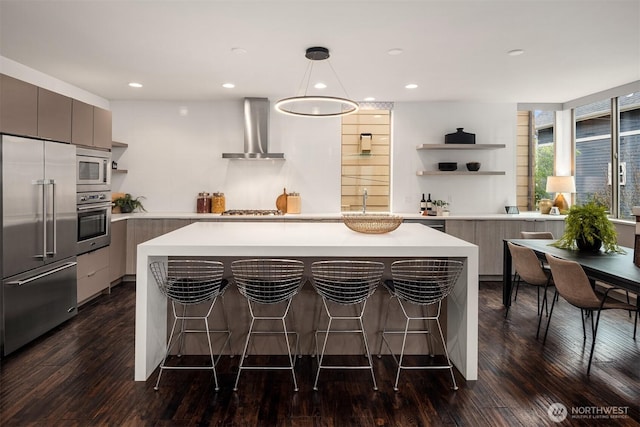 kitchen featuring open shelves, light countertops, built in appliances, wall chimney range hood, and modern cabinets