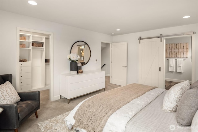 bedroom with recessed lighting, a barn door, a closet, light colored carpet, and a spacious closet