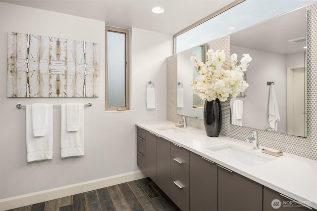 bathroom featuring double vanity, wood finished floors, baseboards, and a sink