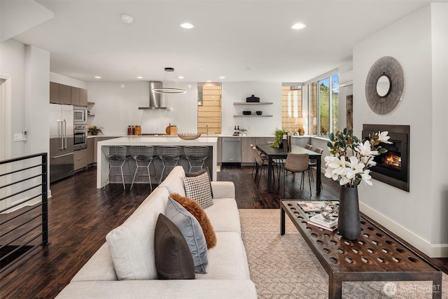 living area featuring dark wood-style floors, a glass covered fireplace, recessed lighting, and baseboards