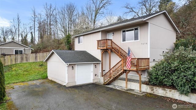 view of front facade with aphalt driveway, stairway, roof with shingles, and fence