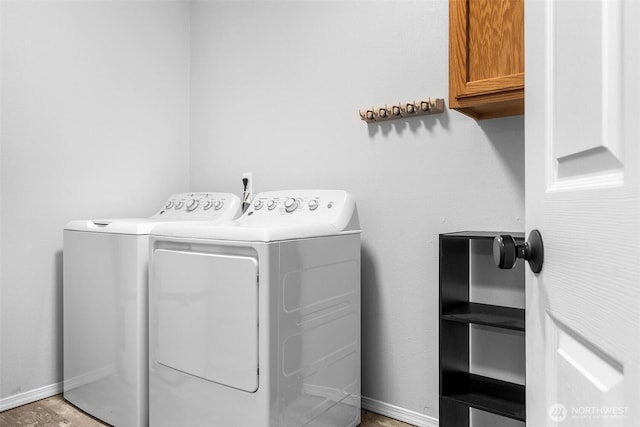 washroom featuring washer and clothes dryer, cabinet space, and baseboards