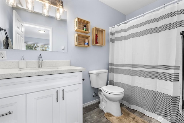 bathroom featuring vanity, toilet, wood finished floors, and baseboards