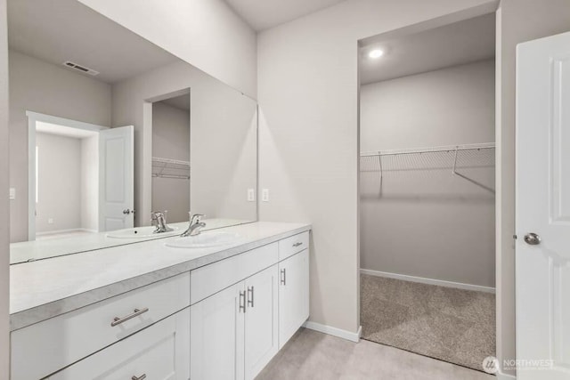 bathroom featuring visible vents, baseboards, a spacious closet, and vanity