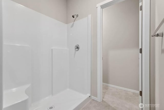 full bathroom featuring a shower stall and baseboards