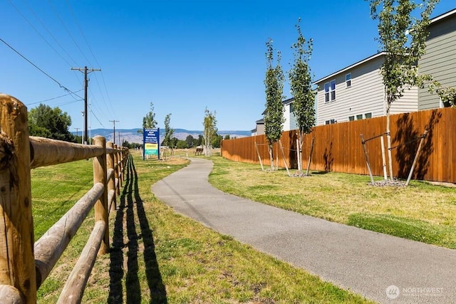 view of home's community with a yard and fence