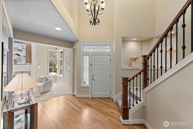 foyer with a chandelier, a high ceiling, baseboards, and hardwood / wood-style flooring