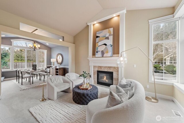 carpeted living room featuring visible vents, lofted ceiling, baseboards, a chandelier, and a tile fireplace