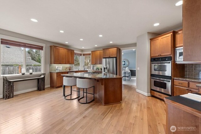 kitchen with backsplash, stainless steel appliances, and light wood-style floors