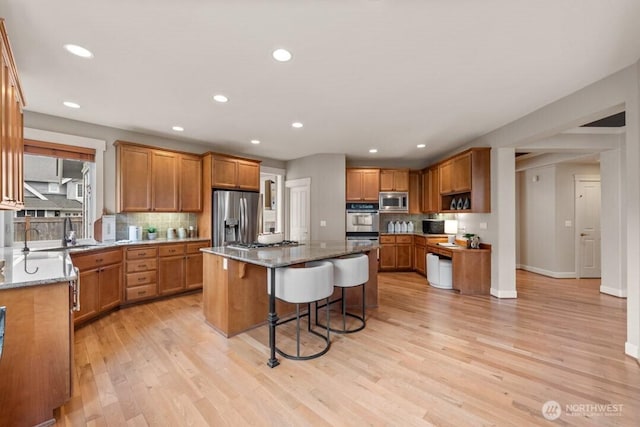 kitchen with stainless steel appliances, a kitchen breakfast bar, a center island, and light stone countertops