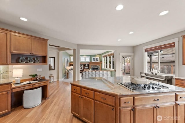 kitchen with recessed lighting, a lit fireplace, and stainless steel gas stovetop