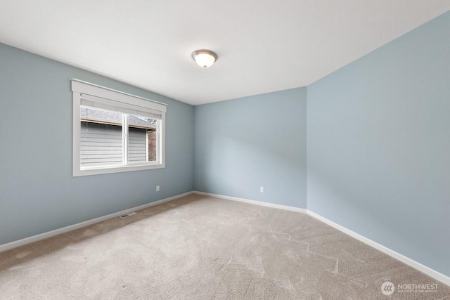 carpeted spare room with visible vents and baseboards