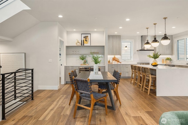 dining space featuring light wood finished floors, recessed lighting, lofted ceiling, and baseboards