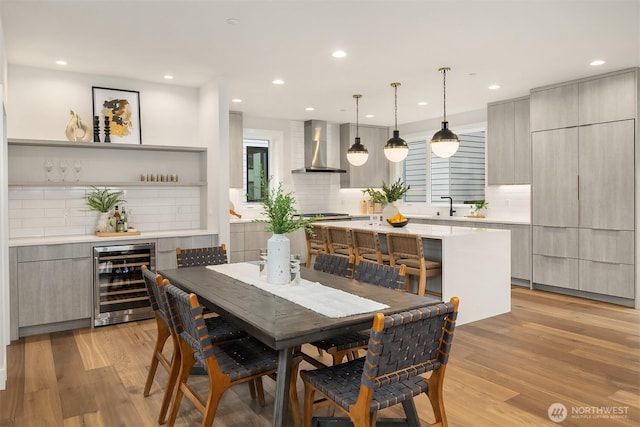 dining space featuring wine cooler, recessed lighting, light wood-style flooring, and a bar