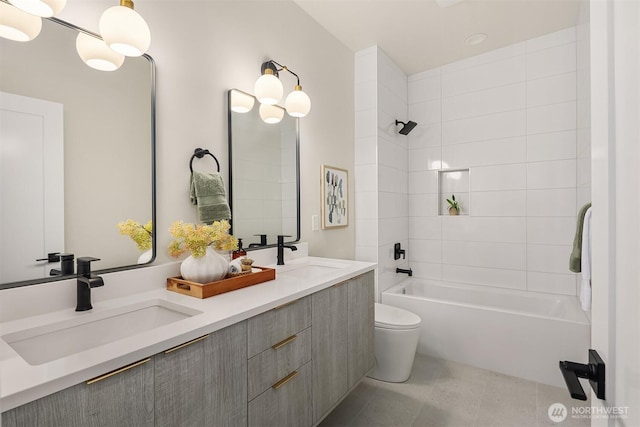 bathroom featuring double vanity, shower / washtub combination, toilet, and a sink