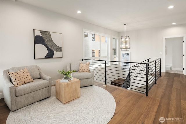 living area with an upstairs landing, a notable chandelier, recessed lighting, and wood finished floors