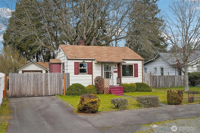 bungalow with a chimney, a front yard, and fence