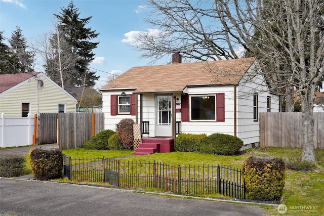 bungalow-style home with a fenced front yard, a chimney, and a front lawn