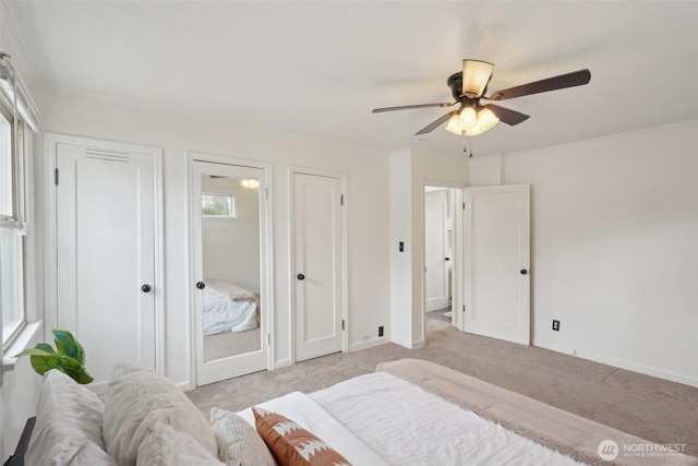 bedroom with baseboards, carpet floors, two closets, and a ceiling fan