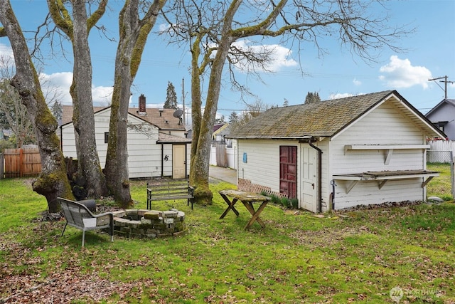 view of yard featuring an outbuilding, fence, and an outdoor fire pit