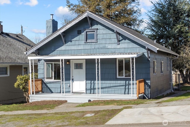 bungalow-style home featuring covered porch and a chimney