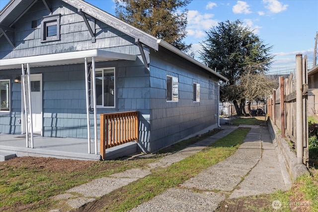 view of side of home featuring a porch and fence