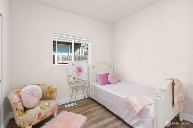 bedroom with visible vents, baseboards, and wood finished floors